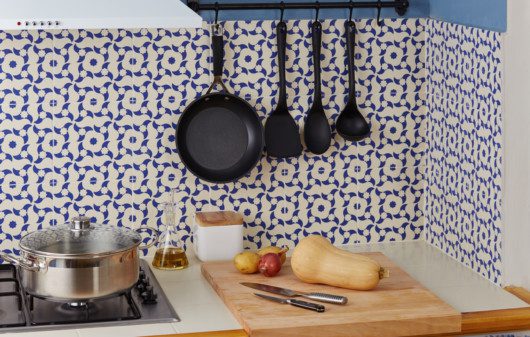 Cozinha revestida com azulejo português com utensílios de cozinha pendurados em ganchos.