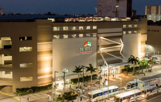 Foto que ilustra matéria sobre shoppings em Fortaleza mostra a fachada do North Shopping à noite vista de cima.