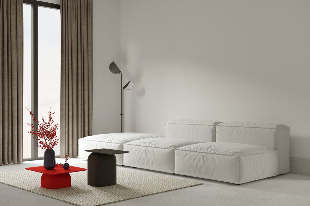 White armless sofa, lamp on the side and red coffee table.