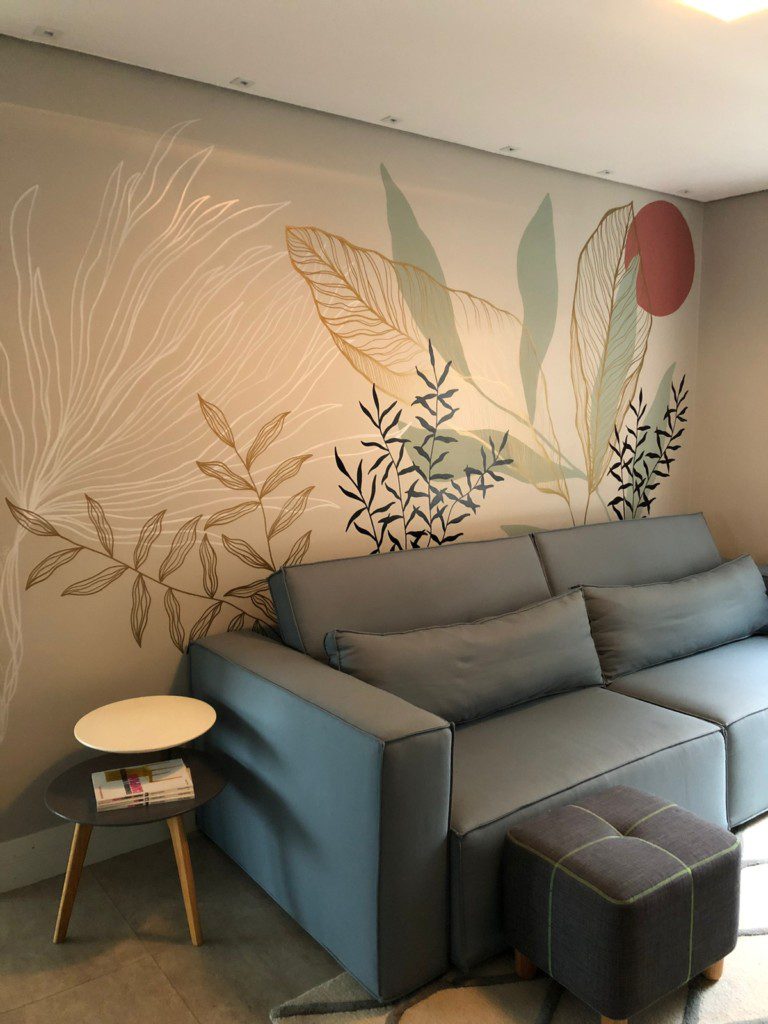 Sala de estar com sofá cinza e arte botânica desenhada à mão na parede.