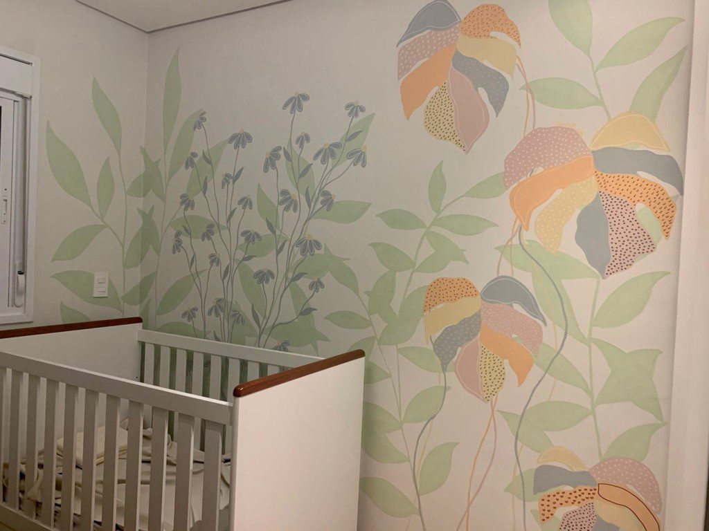 Quarto de bebê com parede desenhada a mão com plantas e flores.