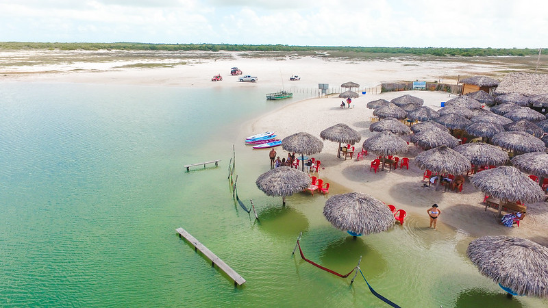 Foto de cima da paisagem. Mostra diferentes tendas, algumas na água e outras na areia. 