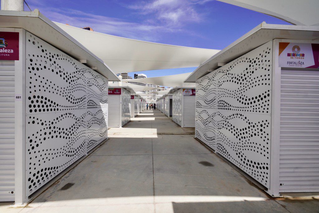 Foto de um corredor com os boxes novos da Feirinha da Beira Mar. Eles são quadrados e brancos. 