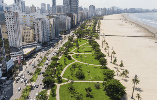 Foto que ilustra matéria sobre orla de Santos mostra a orla da cidade vista de cima, com extensa faixa de areia e uma parte do maior jardim de orla do mundo