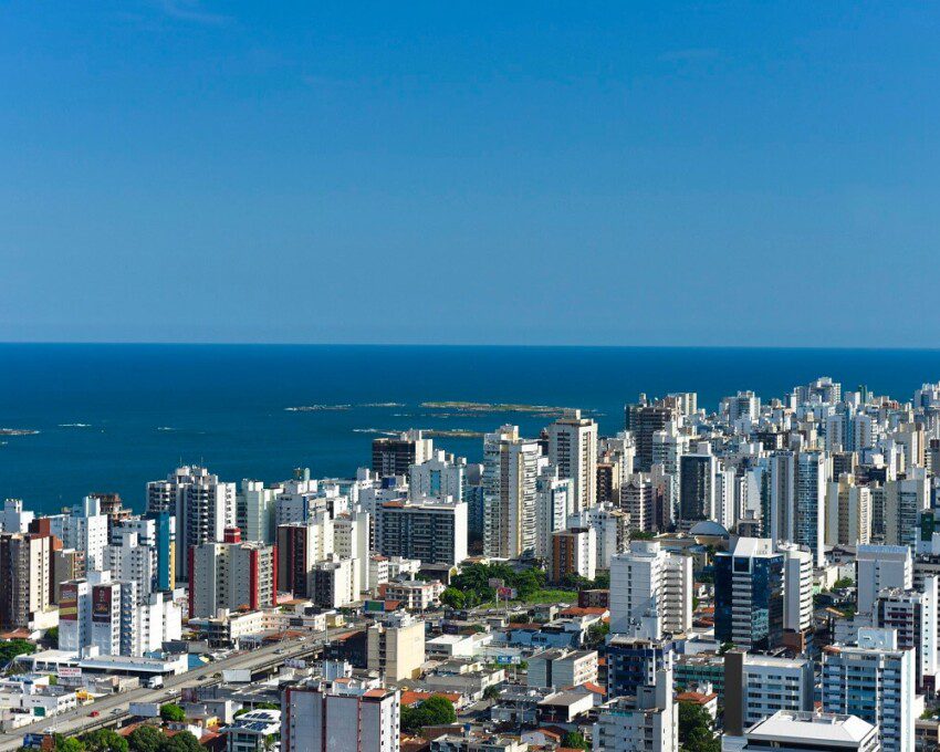 Foto que ilustra matéria sobre bairros de Vila Velha mostra uma visão aérea do bairro Praia da Costa, com muitos prédios e o mar ao fundo. (Foto: Vitor Jubini | MTur)