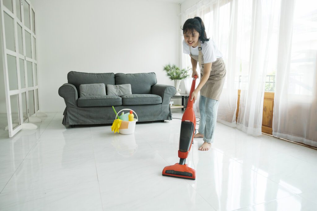 Foto que ilustra matéria sobre como limpar porcelanato mostra uma mulher passando aspirador no chão.
