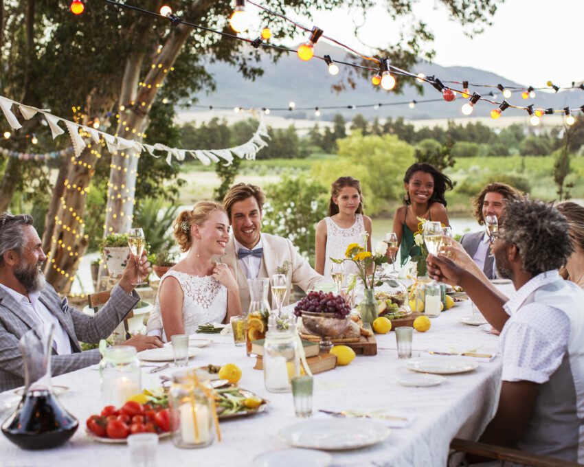 Imagens de diversas pessoas comemorando com os noivos em uma mesa de almoço.
