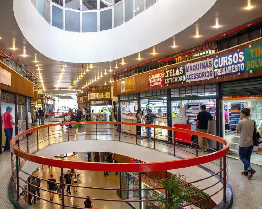 Imagem do primeiro piso do centro comercial Galeria do Rock em São Paulo, que mostra pessoas e andando pelos corredores e lojas abertas. Foto de Mike Peel