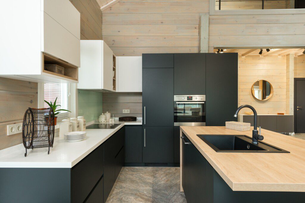 Cozinha com armários preto e branco e detalhes em madeira clara.