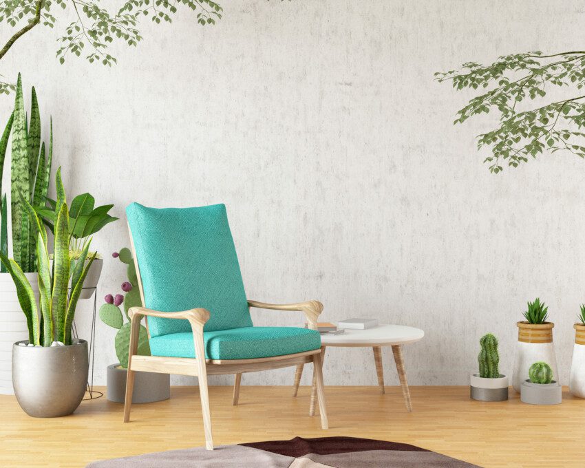 Imagem de uma poltrona verde com detalhes em madeira, mesa de apoio e muitas plantas.