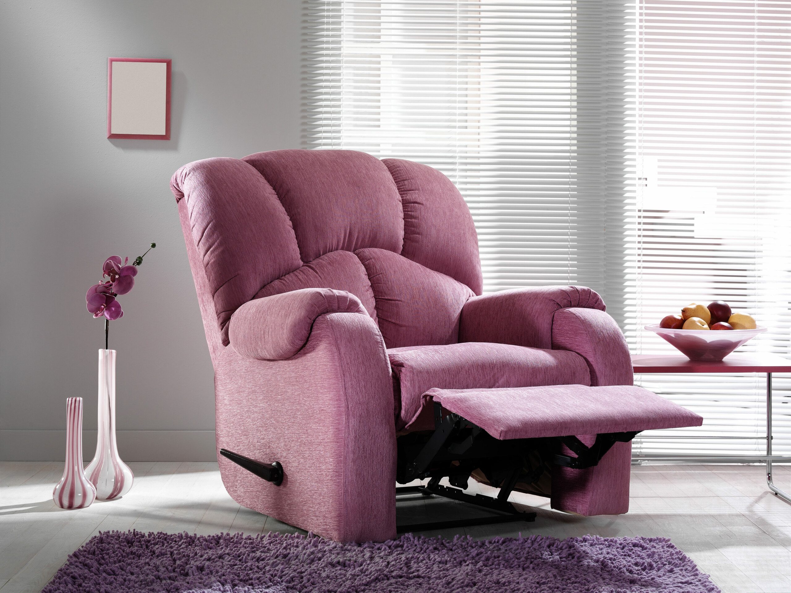 Imagem de uma poltrona modelo reclinável na cor rosa em uma sala de estar. 