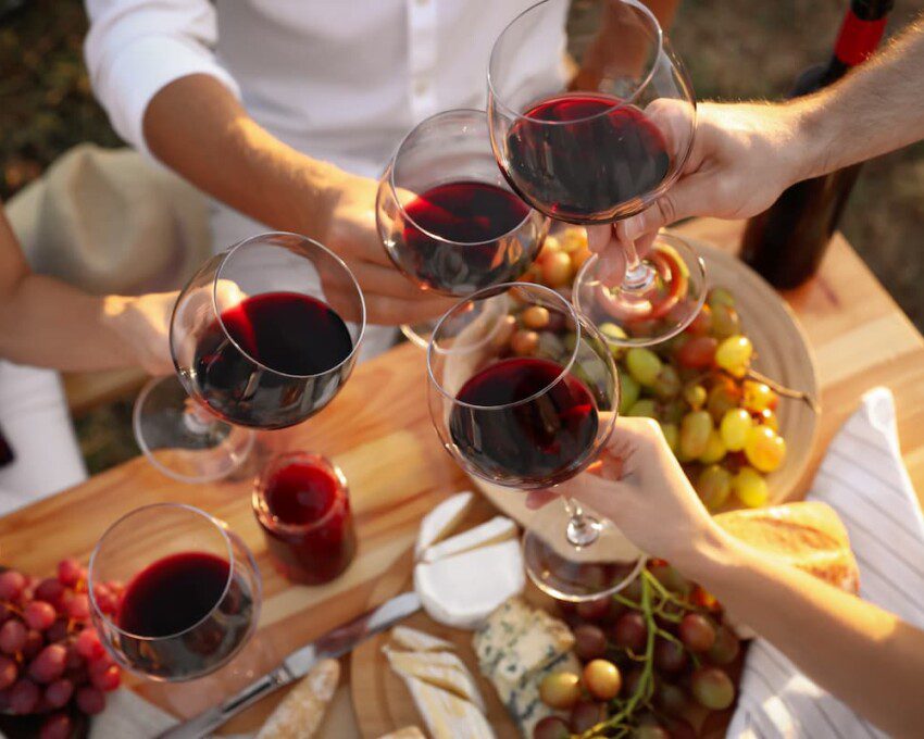 Pessoas comemoram e brindam com vinho e uvas.