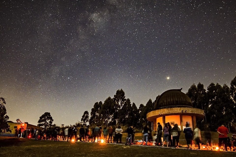 Imagem do Observatório Municipal de Campinas a noite com uma fila de pessoas. 