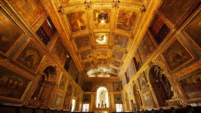 interior da Capela Dourada, com teto, paredes e colunas cobertos por ouro e obras de arte.