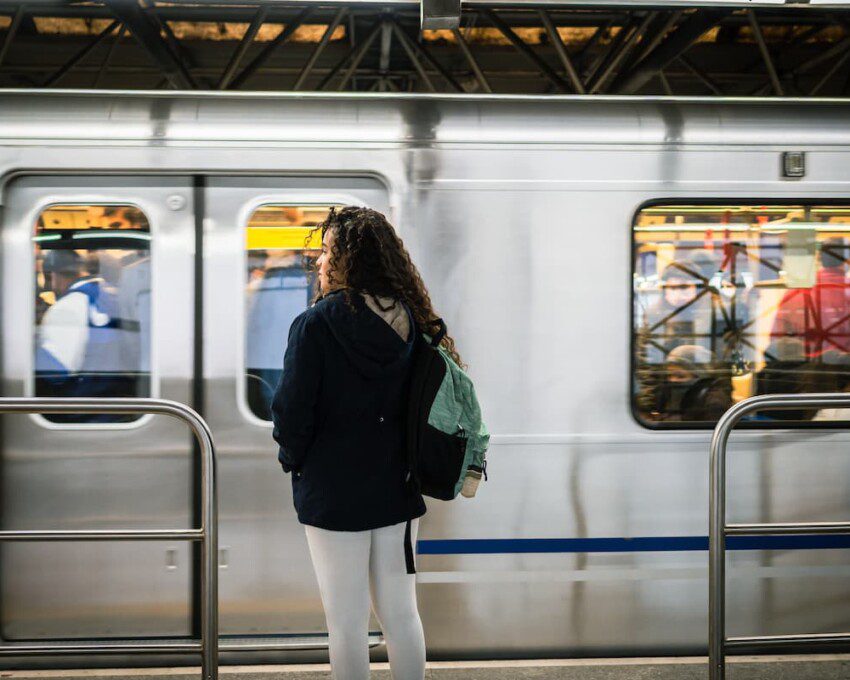 Garota aguarda o metrô parar na estação para embarcar.