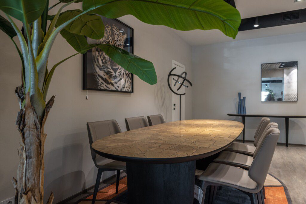 Sala de jantar com mesa de seis lugares em tons de cinza e madeira com um quadro na parede.