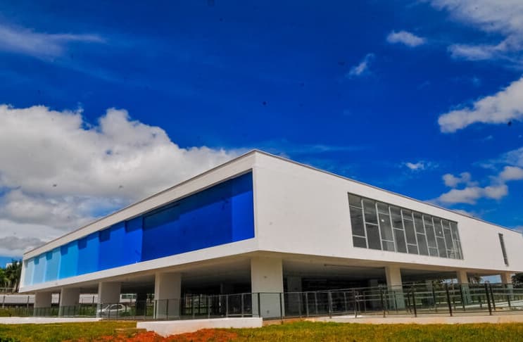 Prédio do Museu de Arte de Brasília, uma edificação moderna, com lateral de vidro e suspenso por colunas de concreto.