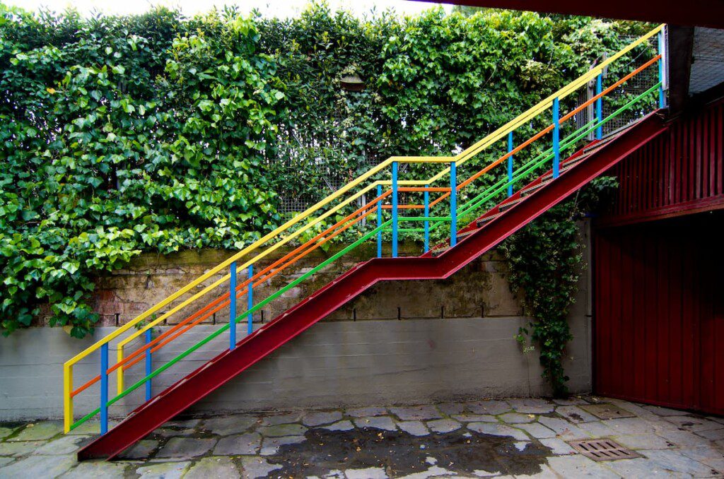 Escada colorida com parede viva ao fundo.