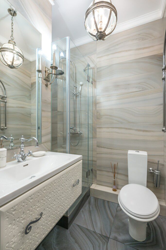 Banheiro com decoração clássica, em tons neutros e móveis brancos e beges. 