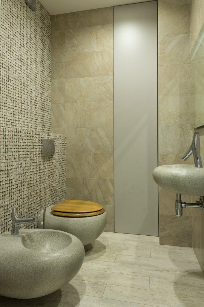 Banheiro em tons neutros, madeiras e parede com revestimento de pastilha. 