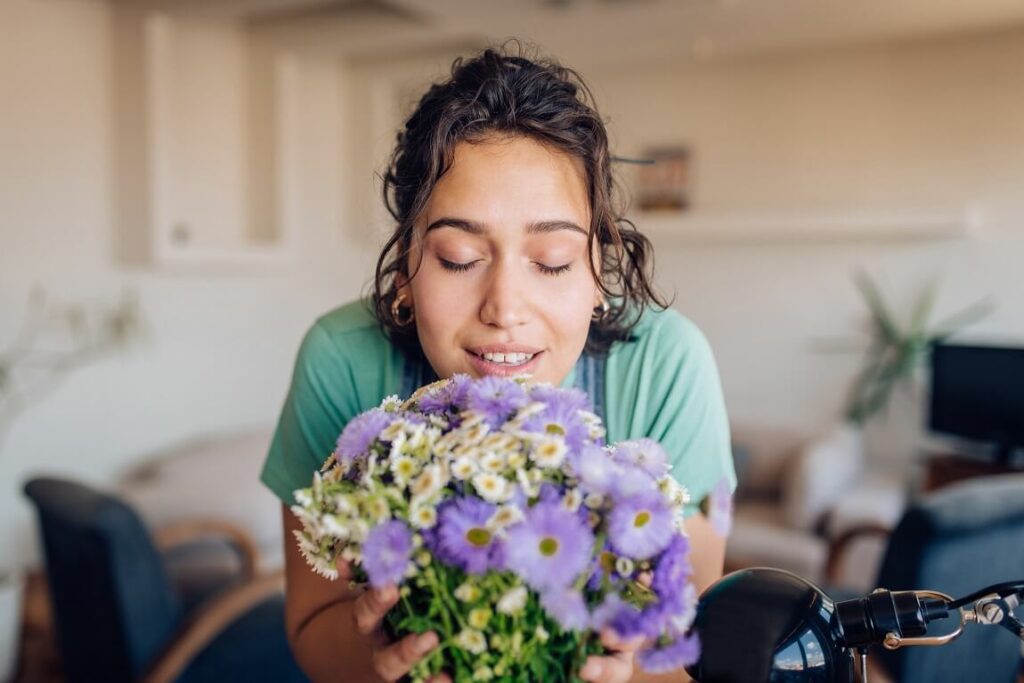 Foto que ilustra matéria com dicas sobre como deixar a casa cheirosa mostra uma mulher cheirando um vaso de flores