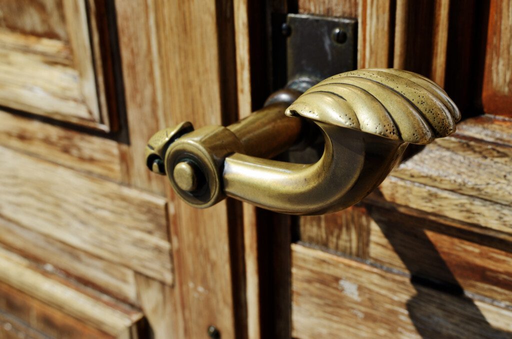 Imagem de uma maçaneta de cobre instalada em uma porta de madeira