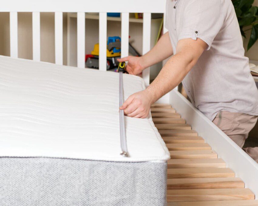 Homem medindo o tamanho de uma cama.