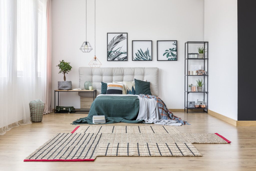  Imagem de um quarto minimalista com tons verdes, cinza e creme, com uma lixeira próxima à cortina 