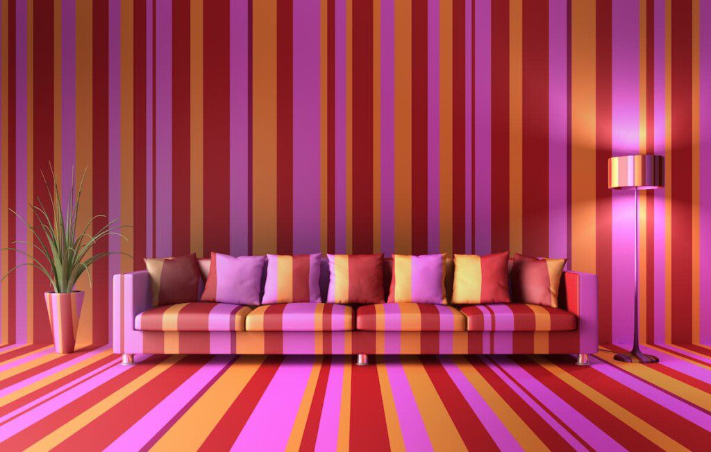 Sala de estar no estilo weirdcore, com papel de parede, piso e sofá que possuem a mesma estampa de listras coloridas.
