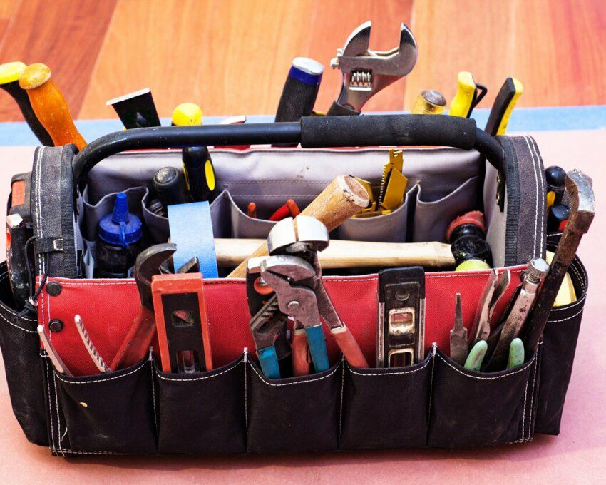 Foto mostra uma bolsa com alça e vários compartimentos repletos de diversos tipos de ferramentas