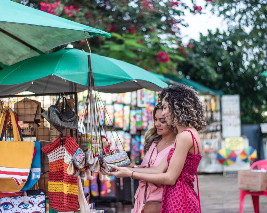 Imagem de duas molheres olhando produtos de artesanato em uma feira de rua para ilustrar matéria sobre as feiras em SP