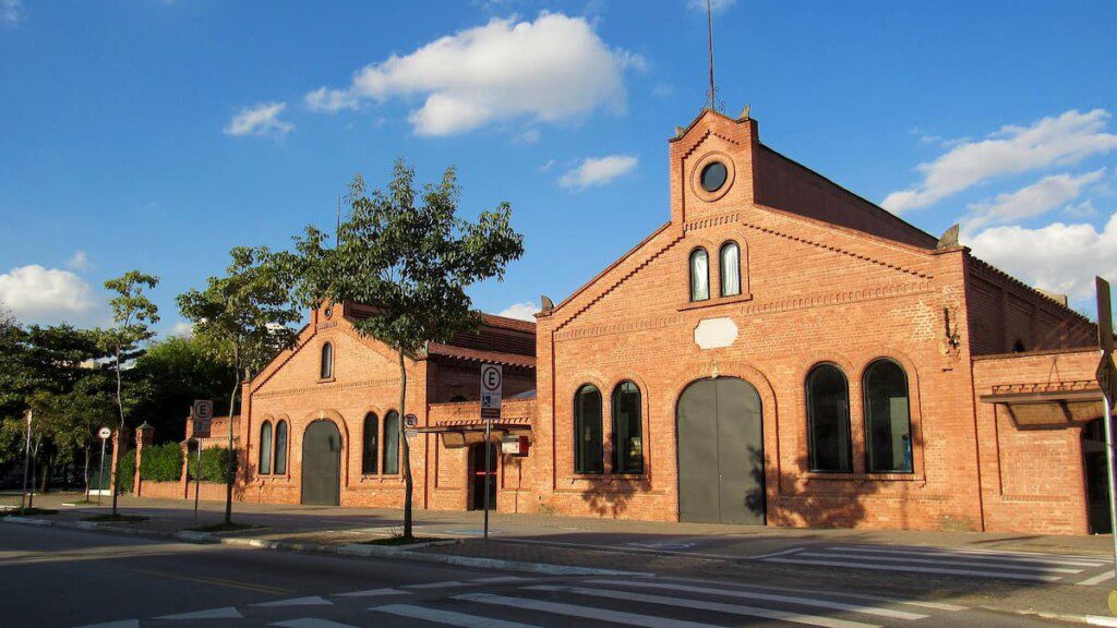 Galpão da Cinemateca Brasileira, em São Paulo. Revestida por muro de tijolos vermelhos. Sua arquitetura externa lembra uma igreja.