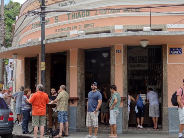 Pessoas em pé, em frente a fachada do Bar do Gomes.