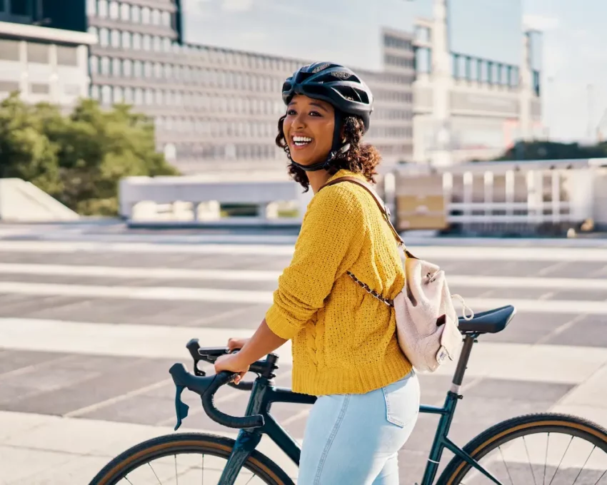 Uma mulher caminha, em uma cidade, ao lado de sua bicicleta.
