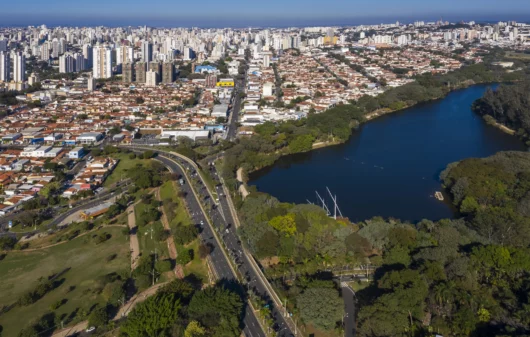 Imagem aérea da Lagoa do Taquaral e de parte da cidade de Campinas ao amanhecer para ilustrar matéria sobre as vantagens e desvantagens de morar em Campinas