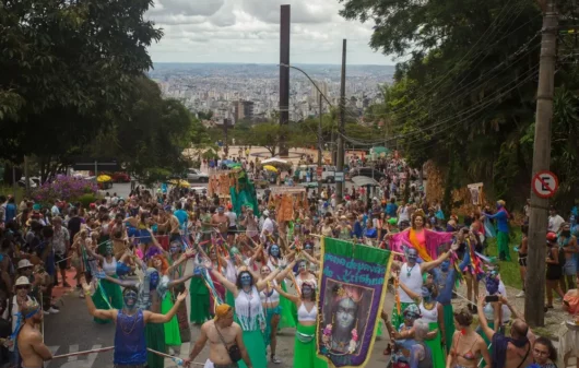 Foto que ilustra matéria sobre Carnaval em BH mostra o bloco Pena de Pavão de Krishna com a Praça do Papa e a cidade de Belo Horizonte ao fundo (Foto: Shutterstock)