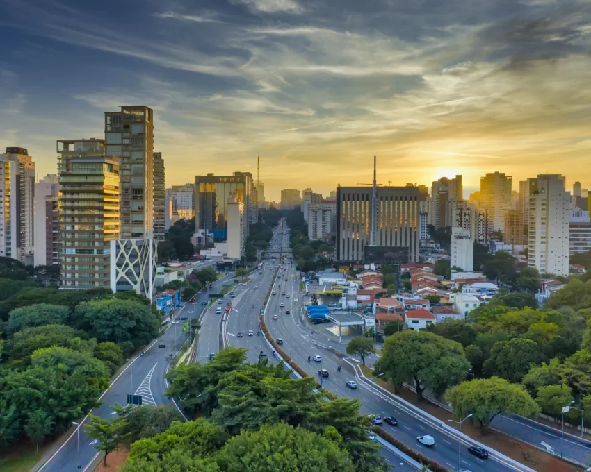 Imagem aérea de carros em pistas cercadas de árvores e prédios durante o anoitecer em São Paulo para ilustrar matéria sobre as cidades com melhor infraestrutura do Brasil
