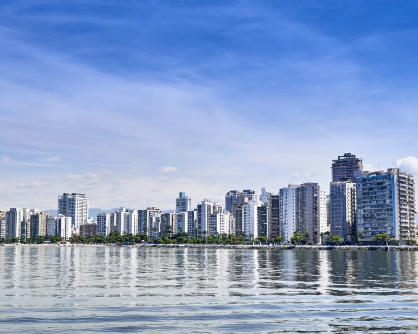 Vista aérea da paisagem urbana de Santos mostra mar e prédios à beira-mar para ilustrar matérias sobre morar em Santos e trabalhar em São Paulo