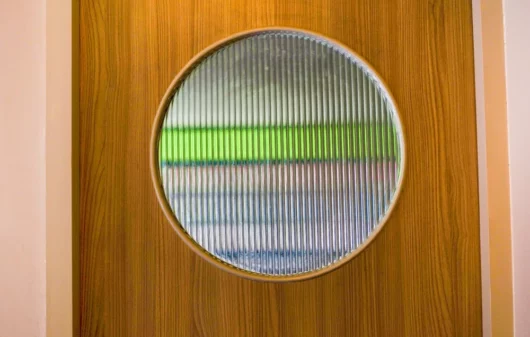 Foto mostra uma janela circular em uma porta de madeira feita com vidro canelado (Foto: Shutterstock)