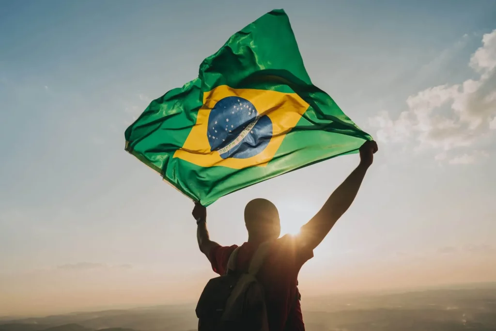 Imagem de um homem de costas segurando uma bandeira do Brasil acima da cabeça para ilustrar matéria sobre as cidades do Brasil mais visitadas