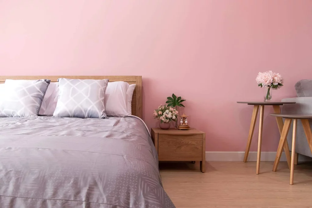 Imagem de um quarto com parede rosa-pálido e uma decoração em tons de cinza para ilustrar matéria sobre cor ideal para quarto de casal
