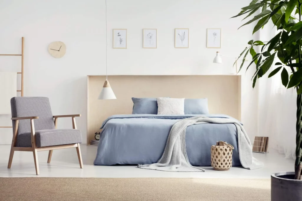 Imagem de um quarto com paredes brancas e uma cama de casal com panos em azul claro para ilustrar matéria sobre cores de tinta para quarto de casal