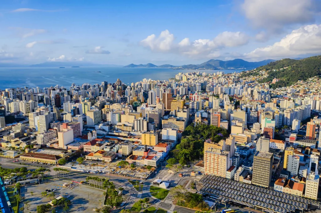 Imagem da vista aérea de Florianópolis, em Santa Catarina, mostra prédios, vegetação e mar ao fundo para ilustrar matéria sobre as cidades mais visitadas do Brasil