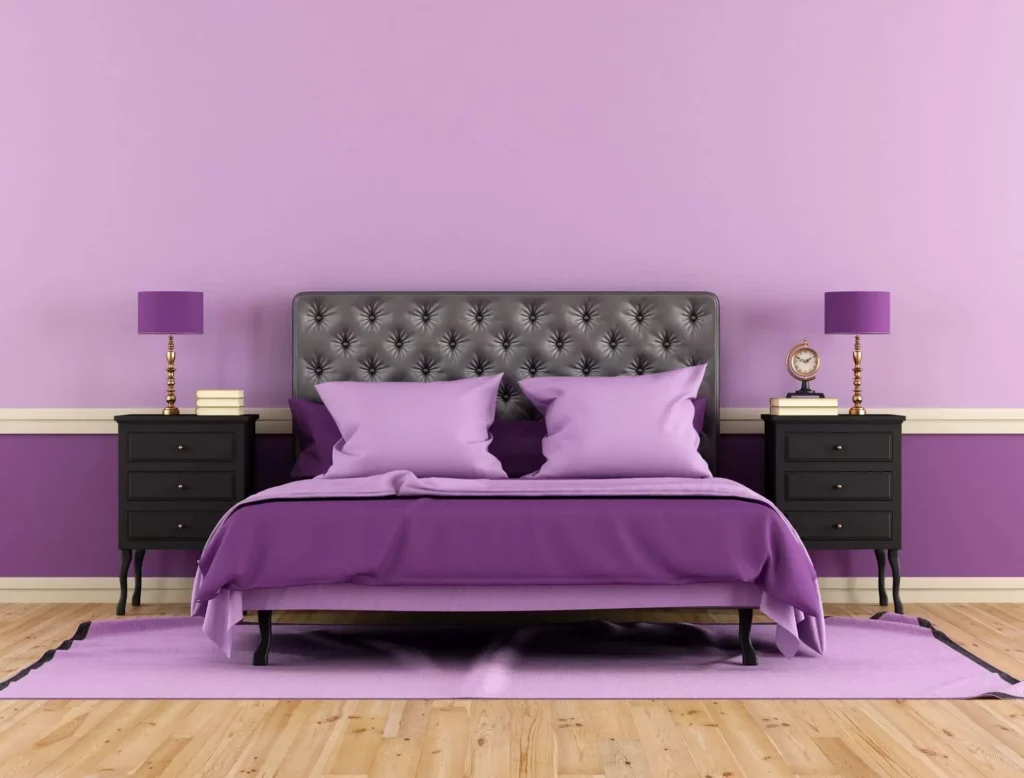 Imagem de um quarto de casal com parede roxo-lilás e decoração no mesmo tom e com detalhes pretos para ilustrar matéria com inspiração de cores para pintar a parede do quarto de um casal