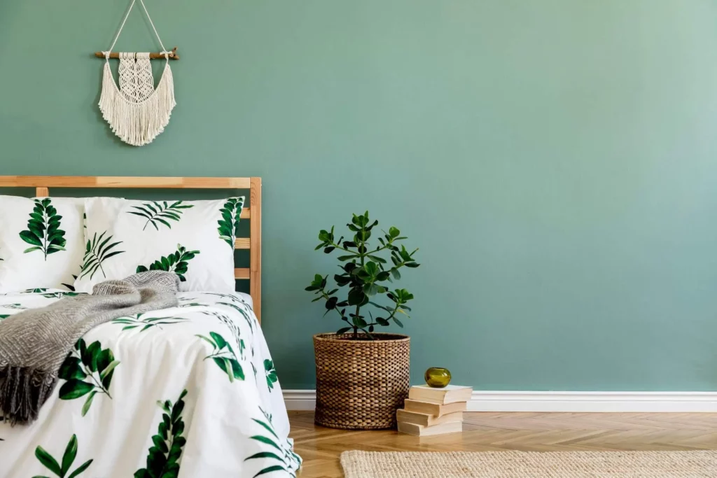 Imagem de um quarto com parede verde-água e uma decoração minimalista com plantas para ilustrar matéria sobre melhores cores para quarto de casa
