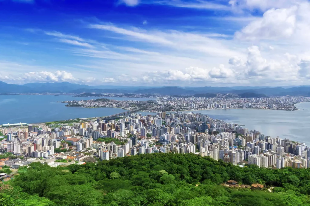 Imagem da vista aérea de Florianópolis mostra prédios, vegetação e mar para ilustrar matéria sobre qual a cidade considerada mais bonita do Brasil
