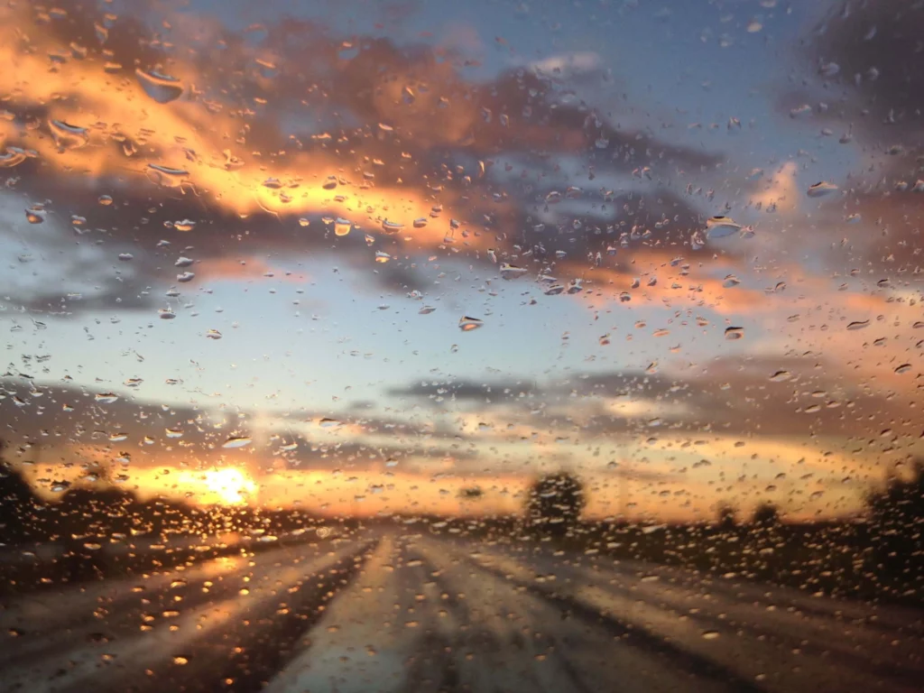 Imagem de uma rodovia através de um vidro com respingos de chuva para ilustrar matéria sobre qual a cidade que mais chove no Brasil