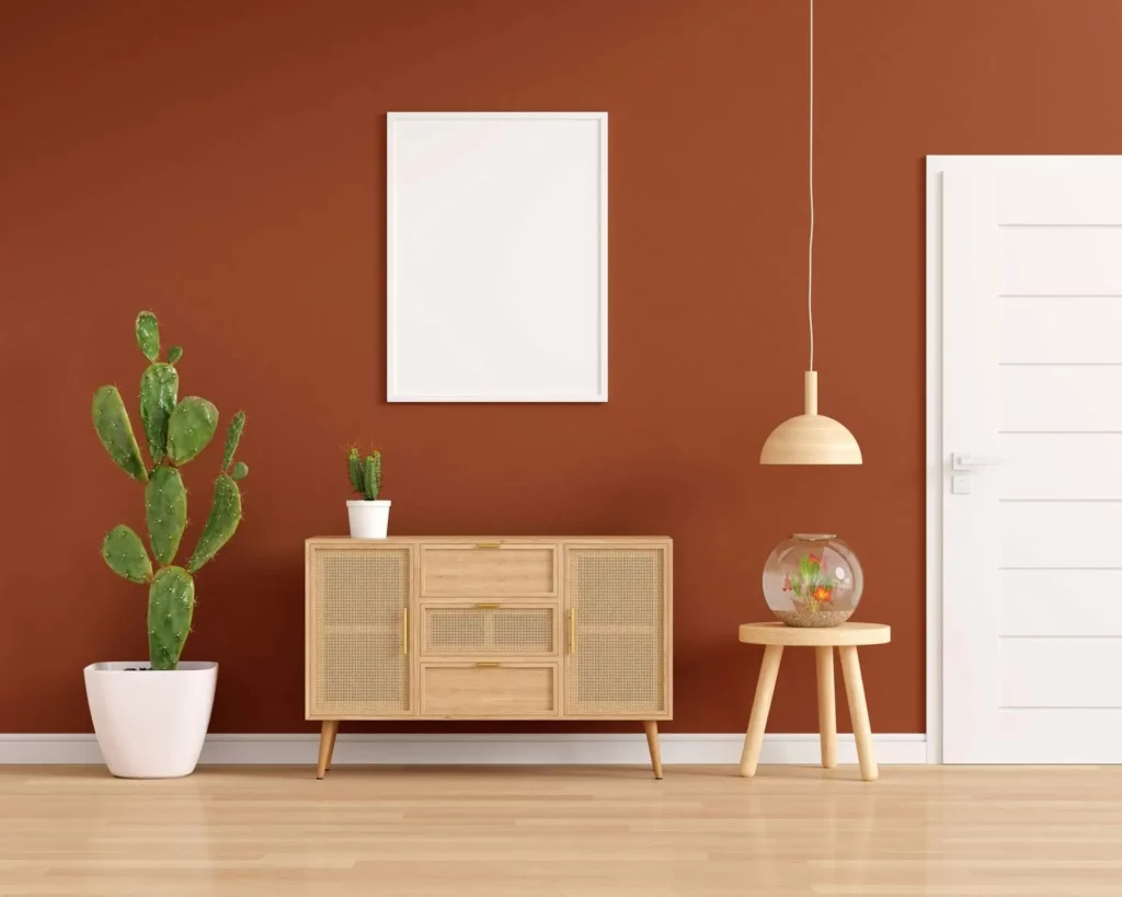Imagem de um cômodo com parede marrom-terracota decorado com elementos amadeirados e um cacto para ilustrar matéria com ideias de tintas para pintar quarto de casal