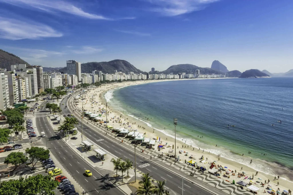 Imagem do litoral de Copacabana mostra mar, faixa de areia, avenida, prédios e vegetação para ilustrar matéria sobre lazer na zona sul do Rio de Janeiro