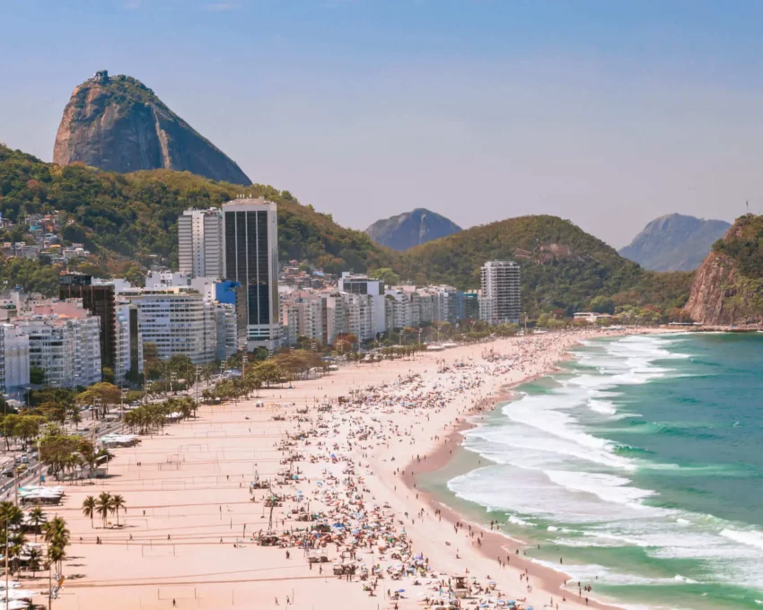 Imagem da praia de Copacabana mostra mar, faixa de areia, prédios e vegetação para ilustrar matéria sobre o que fazer na zona sul do Rio de Janeiro